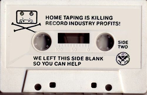 White cassette, side two, printed with a skull-and-crossbones cassette logo and the text: "HOME TAPING IS KILLING RECORD INDUSTRY PROFITS! WE LEFT THIS SIDE BLANK SO YOU CAN HELP." Dead Kennedys, In God We Trust, Inc., 1981 — a parody of the record industry's anti-home-taping campaign.